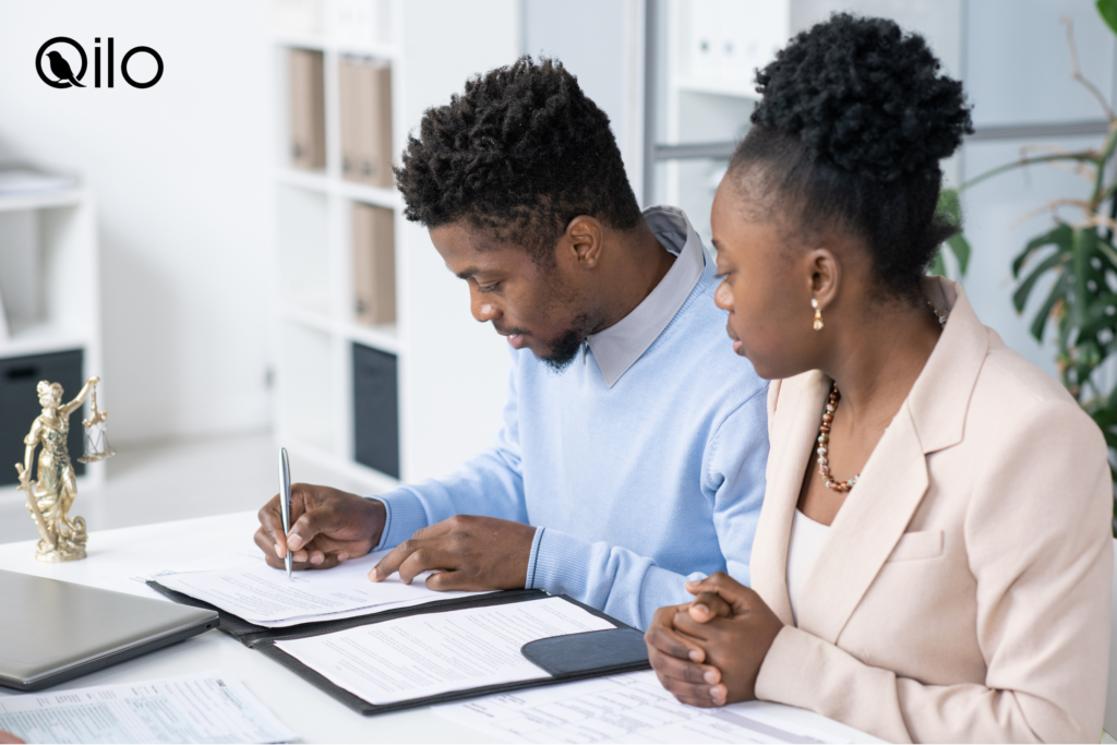 Two people signing paperwork in an office